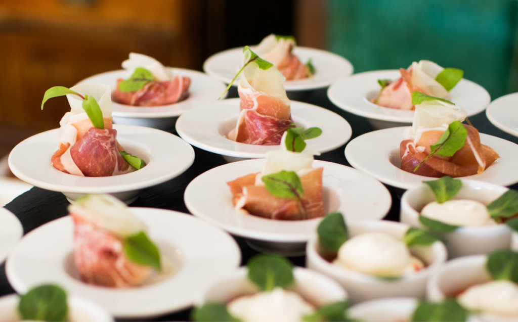 Small plates of serrano ham are lined up, served as canapés.